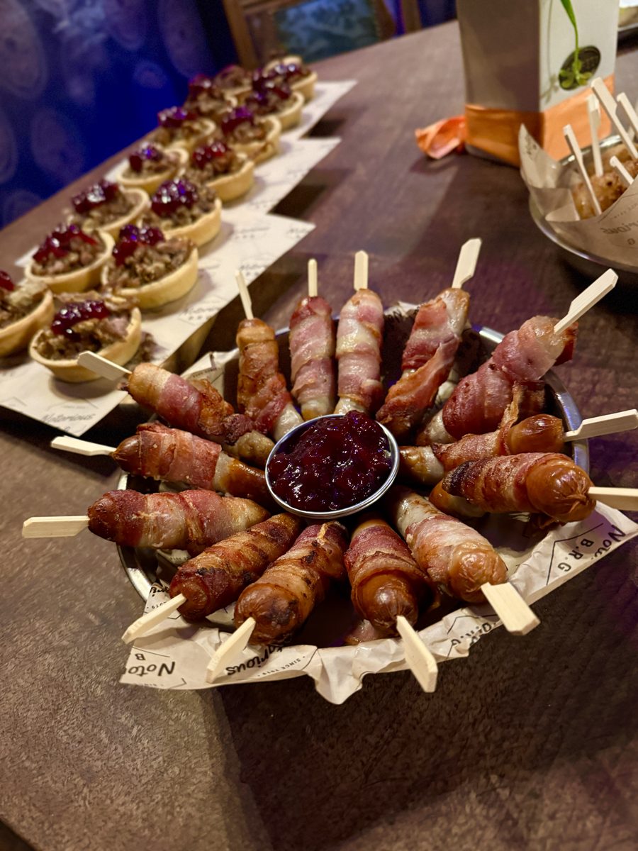 Pigs in blankets on skewers around a pot of cranberry sauce