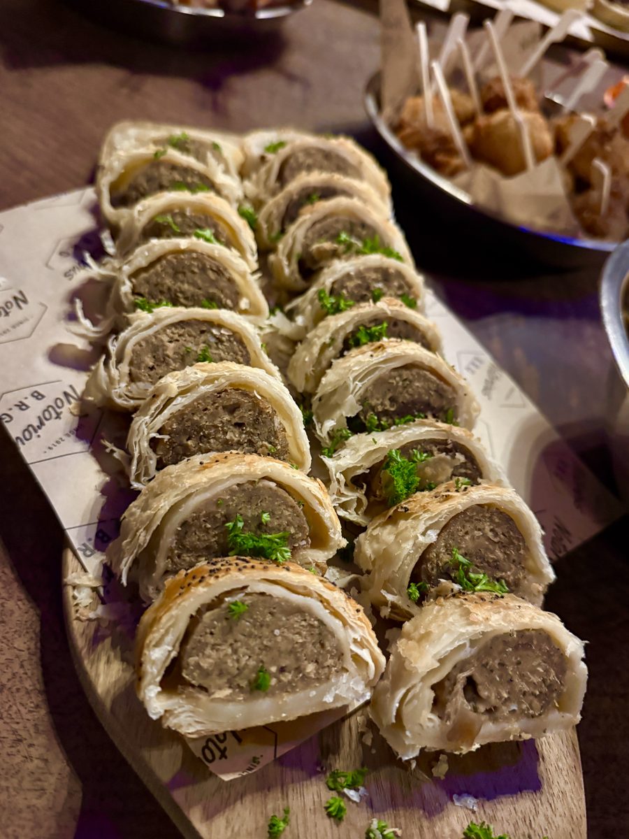 Sliced sausage rolls with herbs on a wooden board