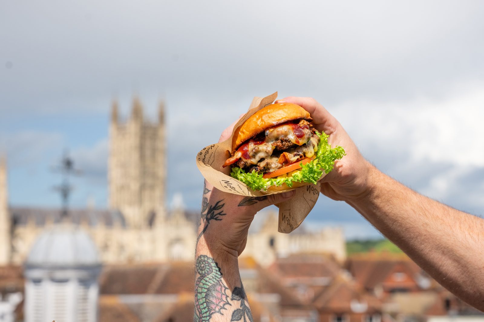 A Notorious BRG burger held up in front of Canterbury Cathedral on The Rooftop