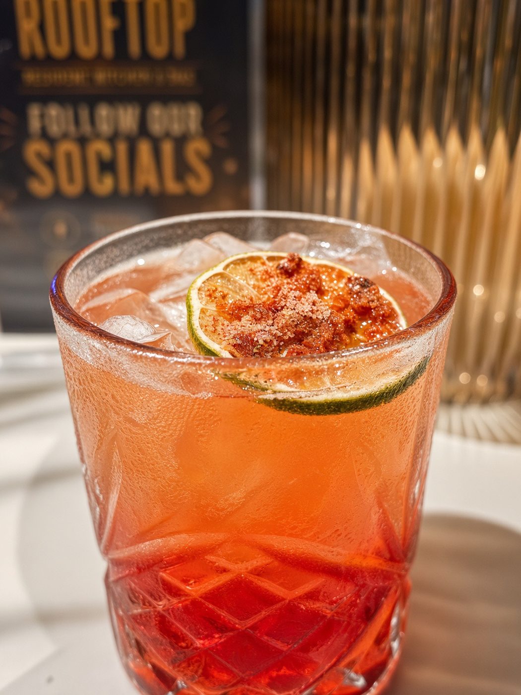 A finished cocktail in a cut-glass tumbler with a dried citrus wheel