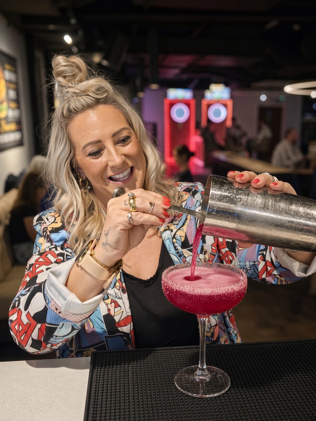 A guest pours a pink cocktail from a shaker into a sugar-rimmed glass at a Rooftop masterclass